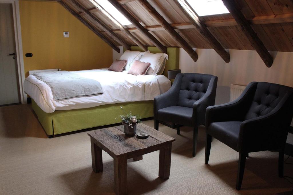 ein Schlafzimmer mit einem Bett, zwei Stühlen und einem Tisch in der Unterkunft De Jagersloft in Wedde