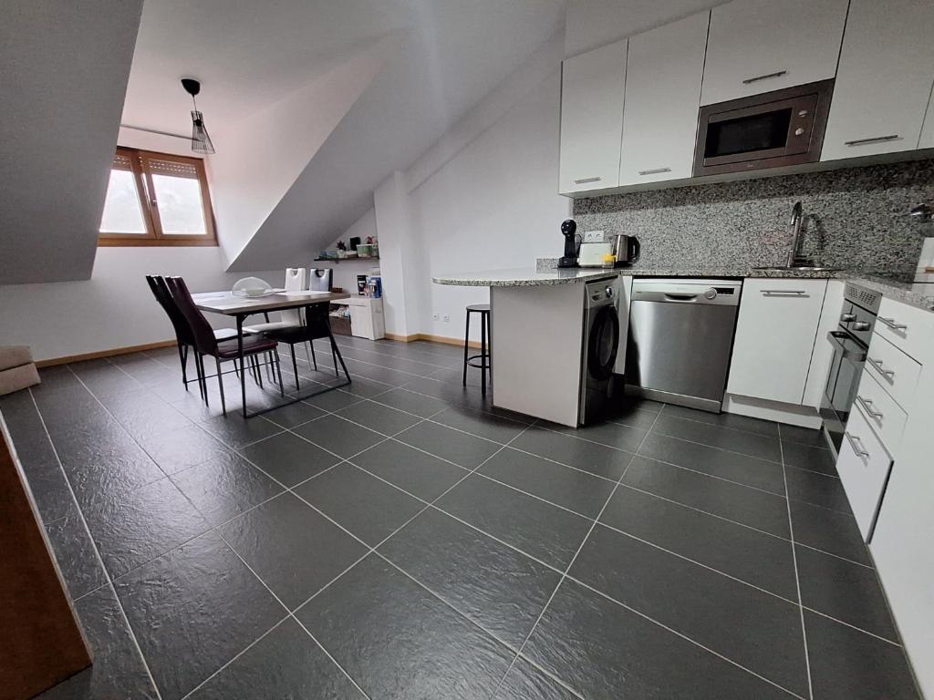 a kitchen with white cabinets and a table with chairs at Aldea Bricia 16 in Posada de Llanes