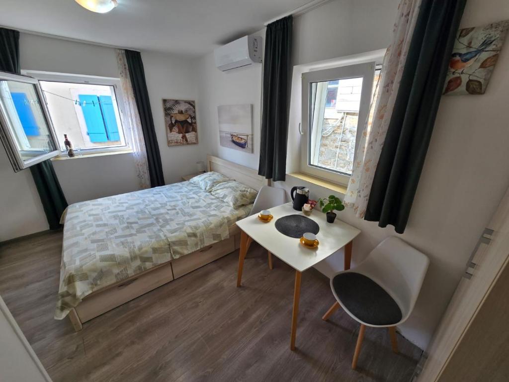a small bedroom with a bed and a table at Apartman Stari grad, Budva in Budva