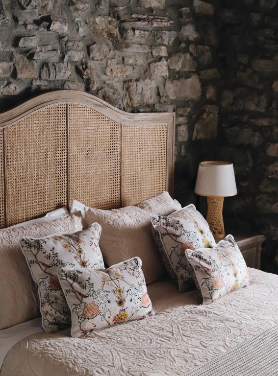a bedroom with a bed with pillows and a stone wall at La Casina de Isoba in Isoba