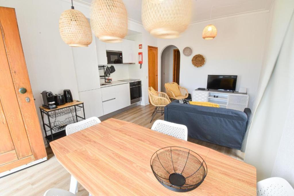 a living room with a table and a kitchen at Beach House Quiaios in Figueira da Foz