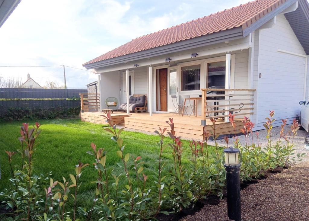 a small white house with a large wooden deck at "Kota coeur de bois" Chalet en bois au domaine de l'Aa in Bourbourg