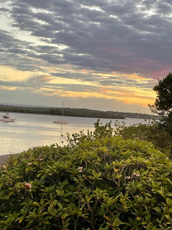 a sunset over a body of water with boats in the water at Salt and Sea-renity in Russell Island