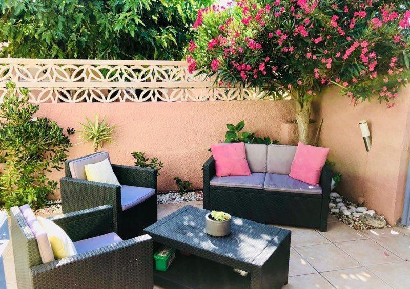 a patio with two chairs and a table and flowers at Maisonnette Les Coraux residence prive avec piscine in Canet-en-Roussillon