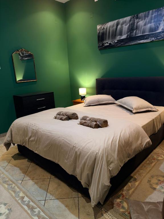 ein grünes Schlafzimmer mit einem großen Bett und zwei Kissen in der Unterkunft AZRA studios in Mytilini