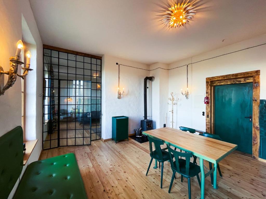 a dining room with a wooden table and green chairs at Hydra - Gutshaus Bückling in Rambin