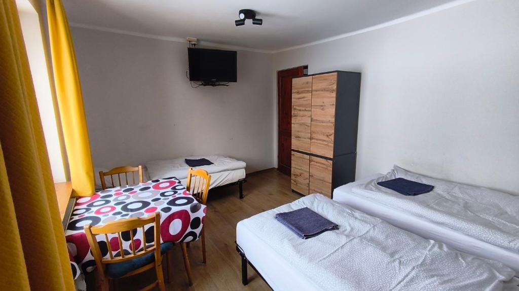 a room with two beds and a table and chairs at Dom Narciarza in Szczyrk