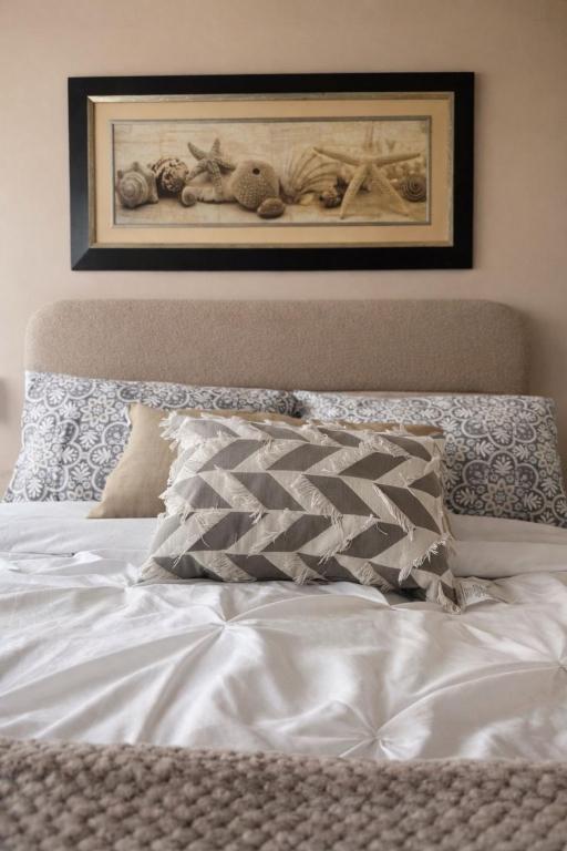a bed with white sheets and a picture on the wall at Casa Palma 2 in La Paz