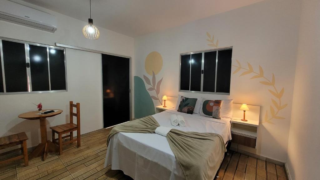 a bedroom with a bed and a table and windows at Pousada Flor do Campo in Serra do Cipo