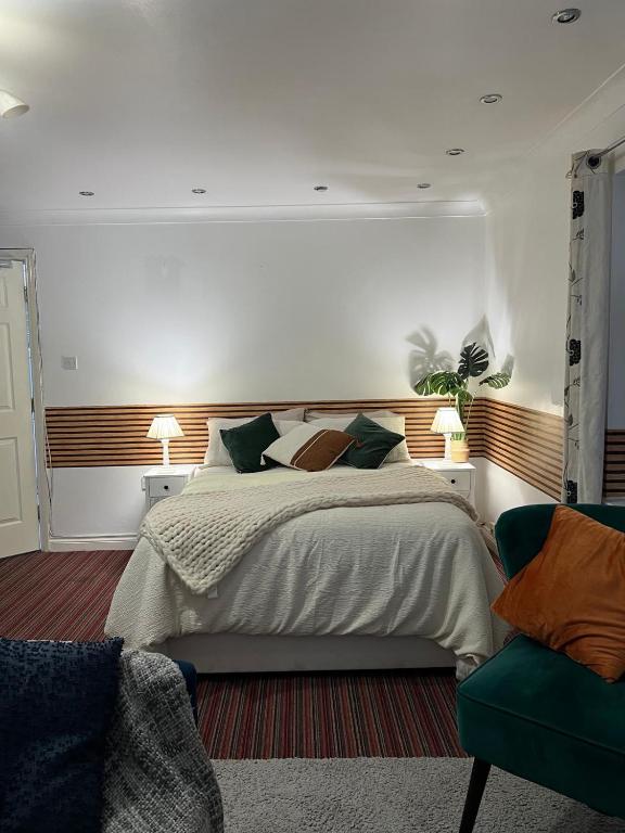 a bedroom with a large bed and a green chair at The Wavers Ideal for airport links NEC JLR in Marston Green