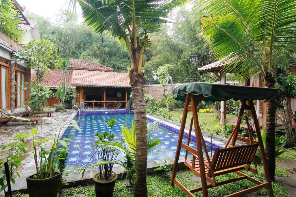 a garden with a swing and a swimming pool at Joglo Mandapa Boutique Hotel in Yogyakarta