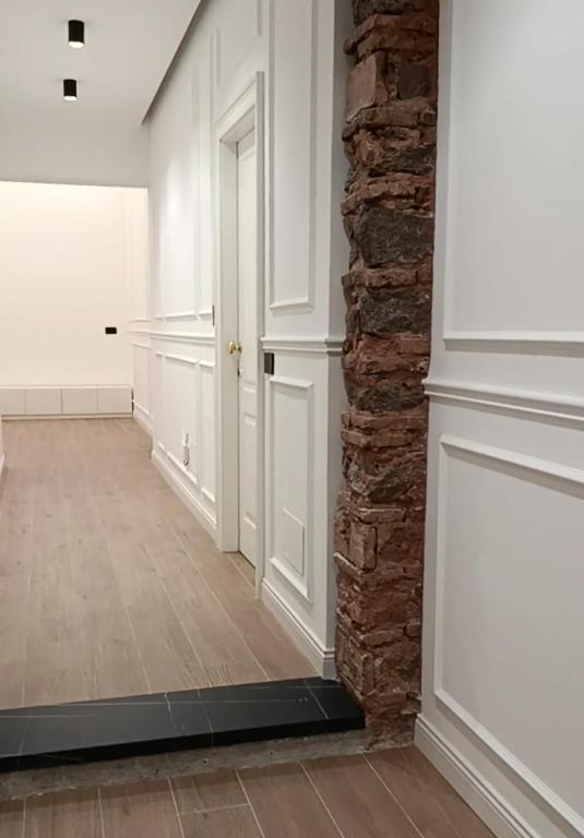 a hallway with white walls and a brick wall at Ursino inn camere e suite in Catania