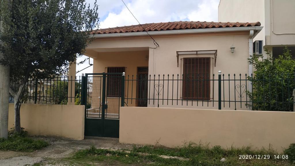 a white house with a black fence in front of it at 150 metres from the beach dafnes Patra in Patra