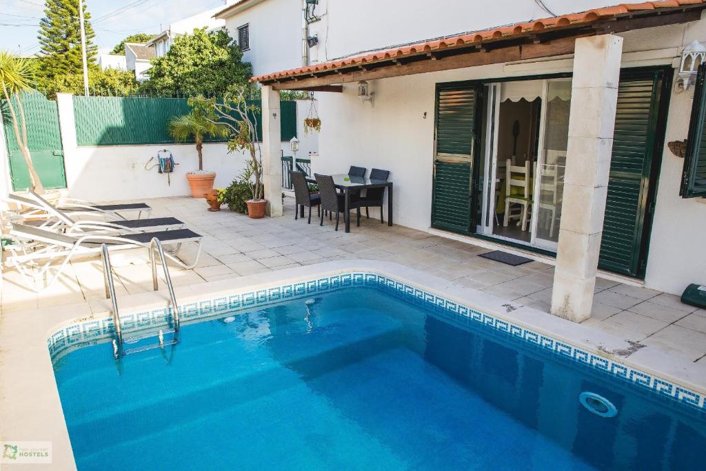 a swimming pool in front of a house with a table at Help Yourself Hostels - Carcavelos Coast in Carcavelos