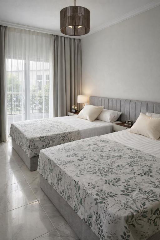 a hotel room with two beds and a large window at Arian North Coast Chalet Santorini Resort El Alamein in El Alamein