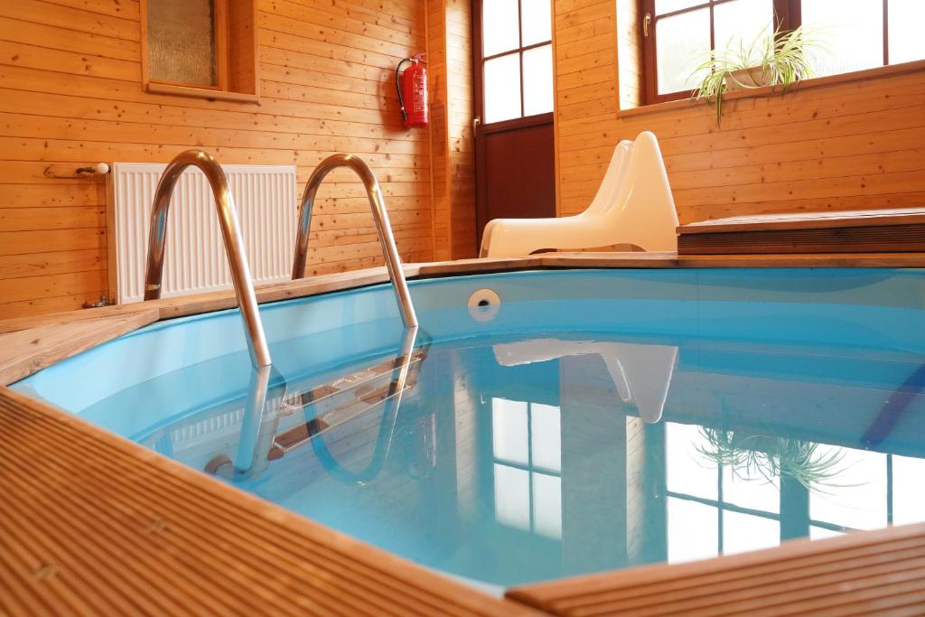 a swimming pool in a house with a chair at Wellness hotel Sauna in Malá Morávka
