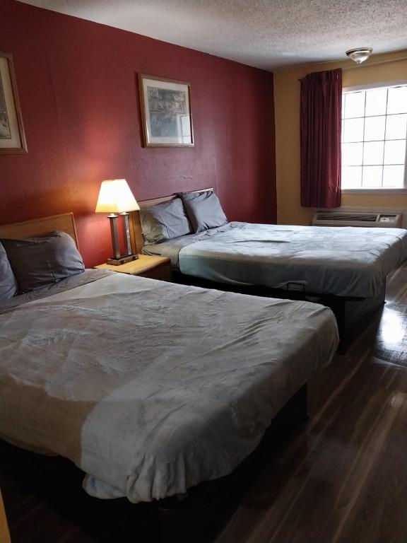two beds in a hotel room with red walls at 2 Queen Beds Hotel Room 237 in Jackson