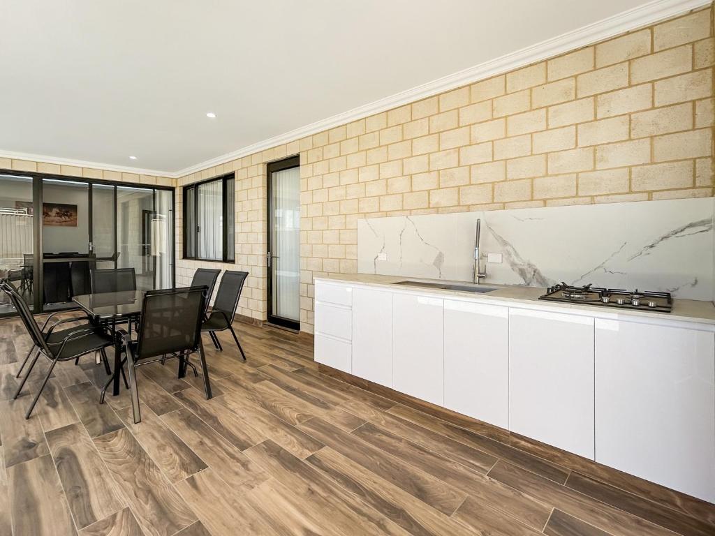 a kitchen with white cabinets and a table and chairs at Spacious 4 bed home with open plan living in Perth