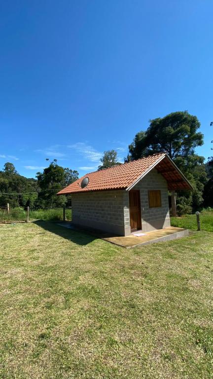 a small house with a grass field next to it at Chalés recanto dos oliveira in Camanducaia