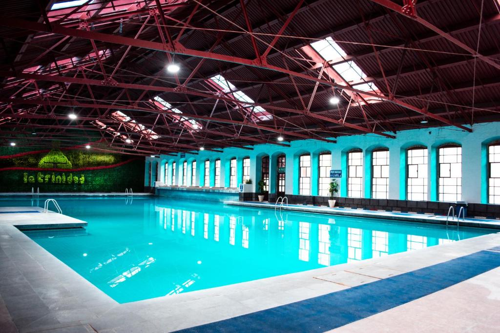a large swimming pool with blue water in a building at Centro Vacacional La Trinidad in Santa María Atlihuetzián