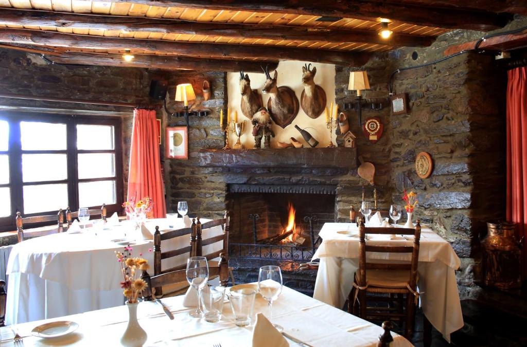 a dining room with two tables and a fireplace at Hotel Can Borrell in Meranges