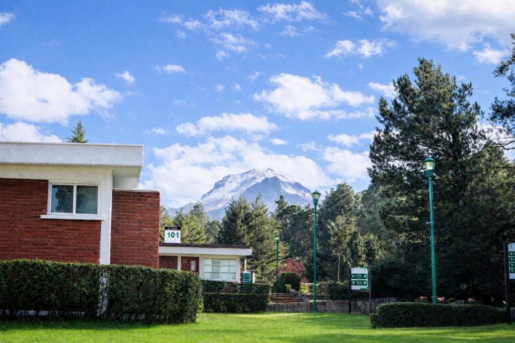 a building with a mountain in the background at Centro Vacacional Malintzi in Guadalupe