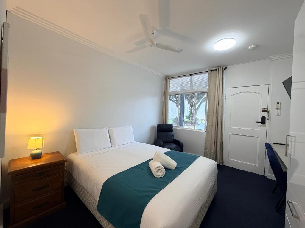 a bedroom with a bed and a desk and a window at Pacific Motel Taree in Taree