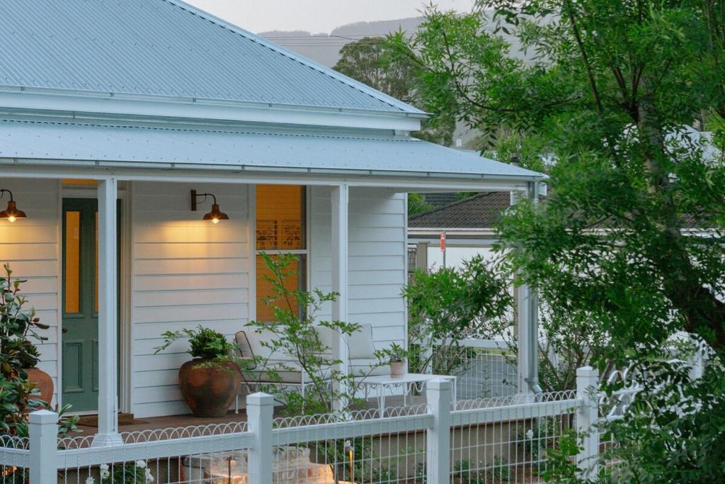 a white house with a white fence in front of it at Greta Cottage, Berry in Berry