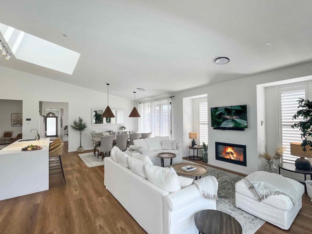 a living room with white furniture and a fireplace at Florette's Pool Suite in Pokolbin