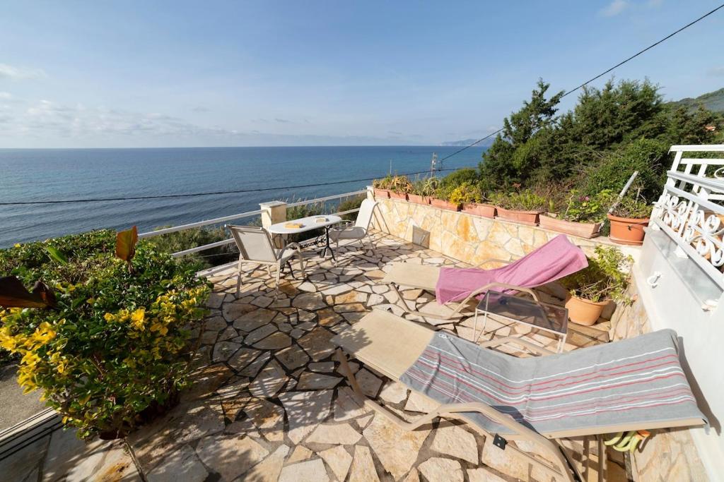 a patio with chairs and a table and the ocean at Oceanfront Studio at Paramonas Beach in Paramonas