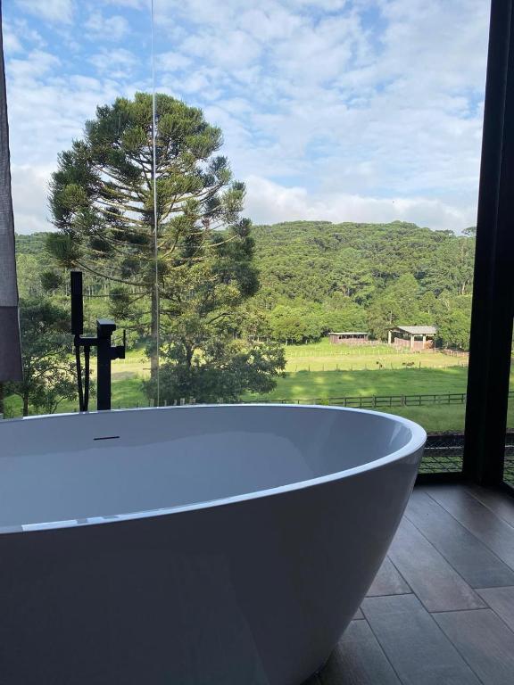 a bath tub in front of a window with a view at Cabanas Grande Passo in Quatro Barras
