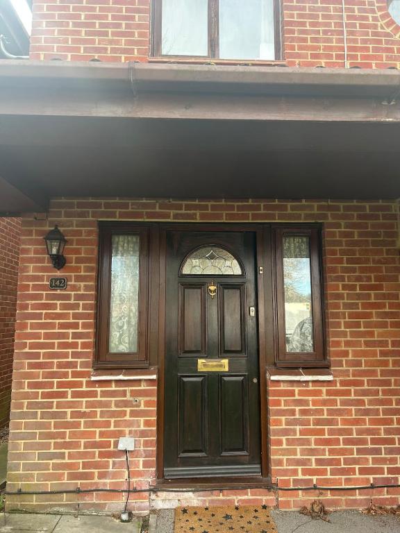 a brick house with a black door and windows at Stylish Home With Full Amenities in Yiewsley