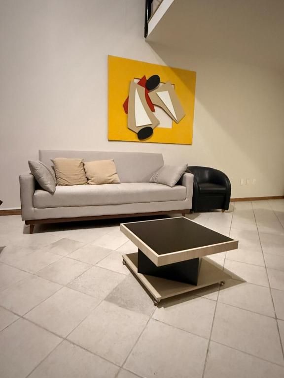 a living room with a couch and a painting at Apartamento Jaragua do sul in Jaraguá do Sul