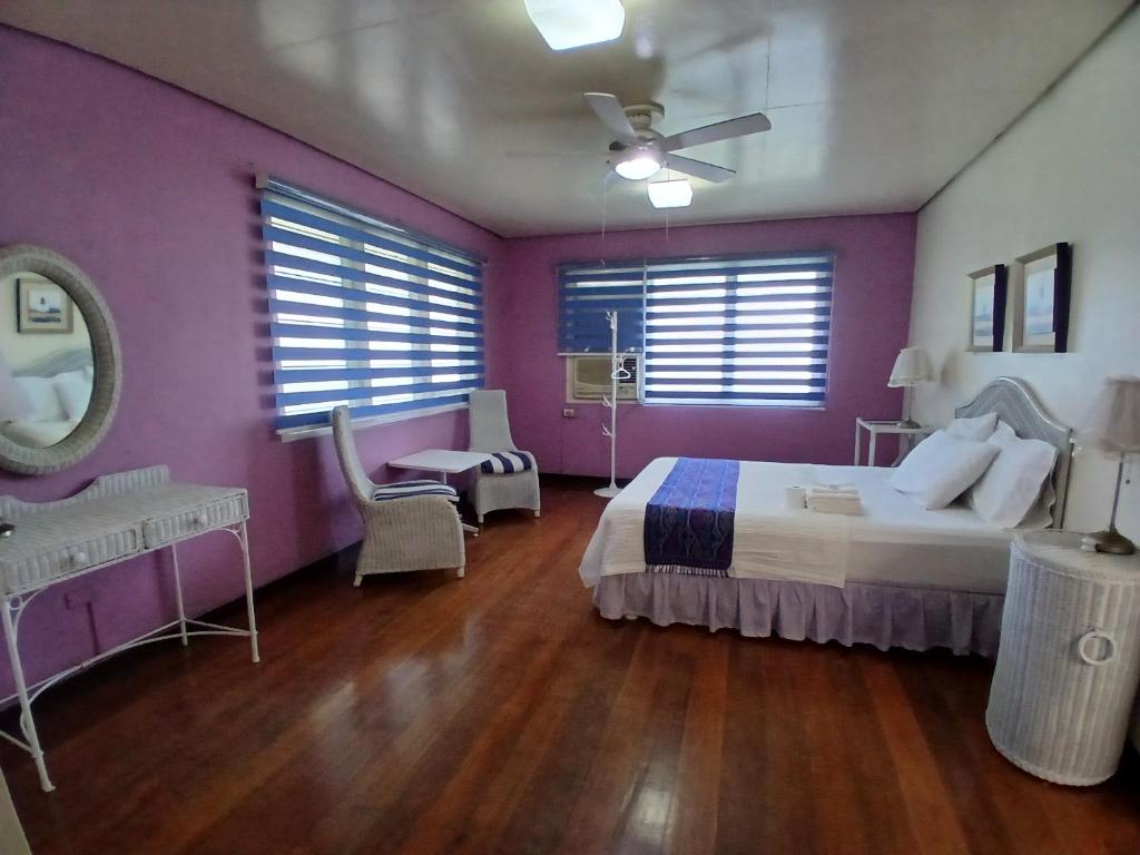 a bedroom with purple walls and a bed and a mirror at Casa Joaquin BnB in Manila