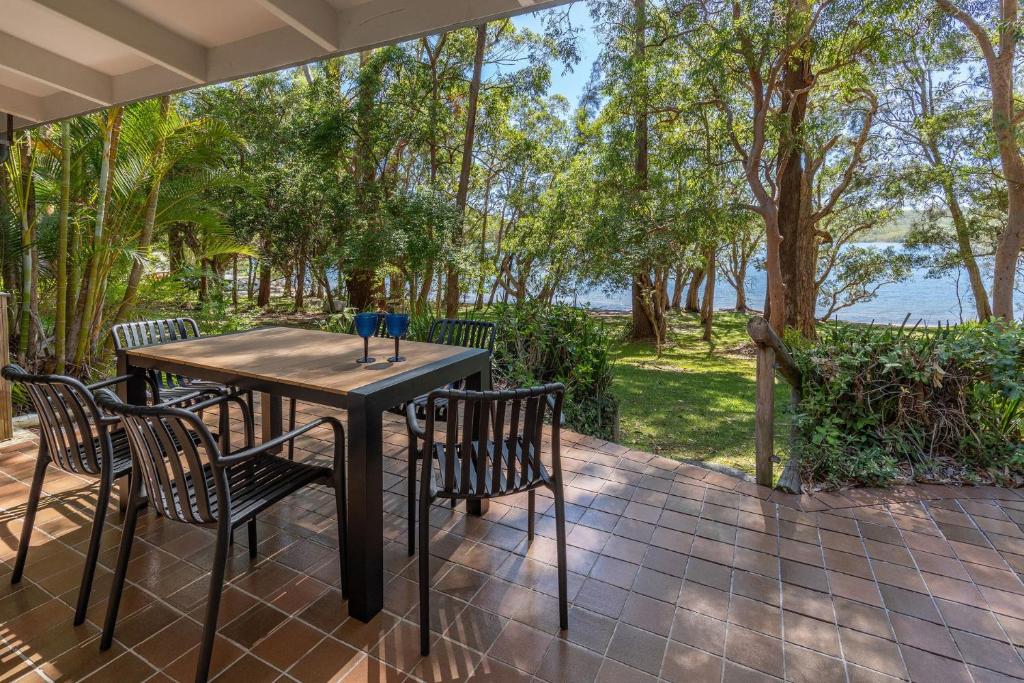 a table and chairs on a patio with a view of the water at Sandpiper 11 in Smiths Lake