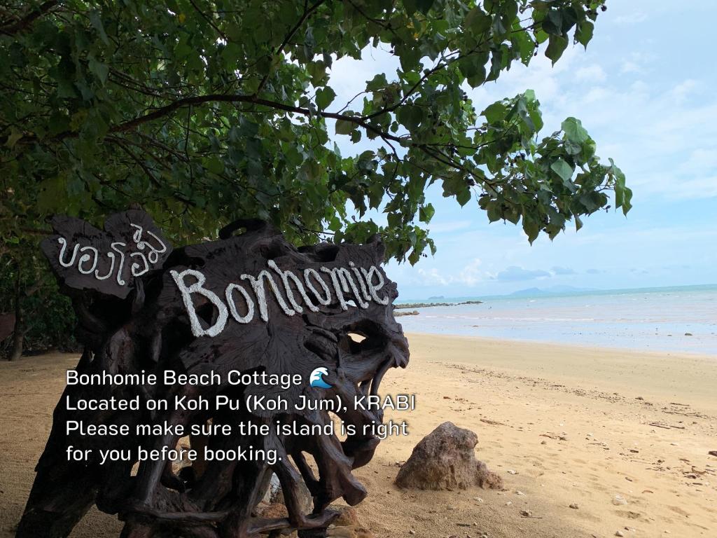 a sign on a beach with a tree at Bonhomie Beach Cottage in Ko Jum
