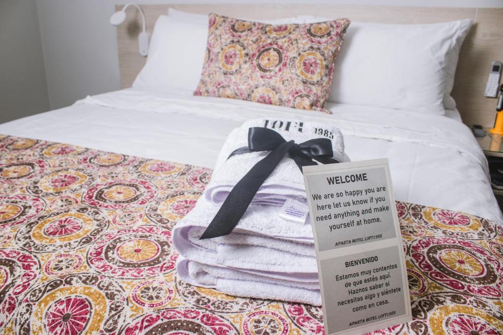 a pile of towels on a bed with a sign on it at Aparta Hotel Loft 1985 Awaliba in Puerto Gaitán