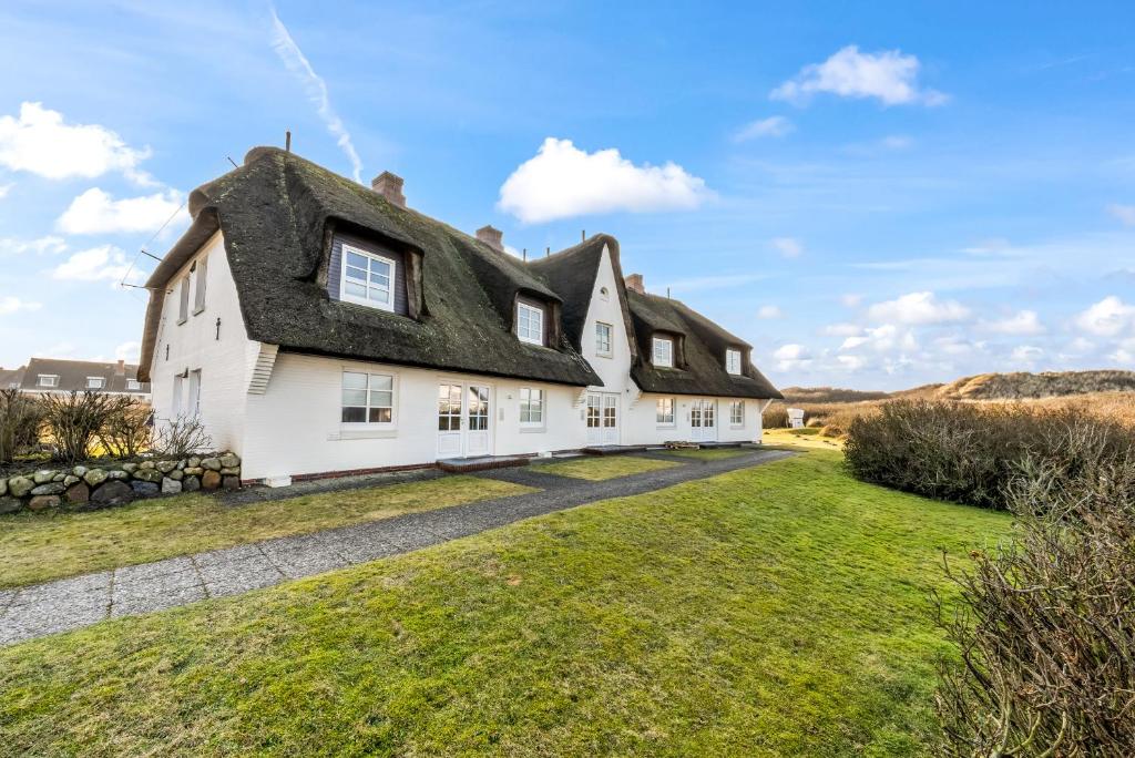 an old white house with a thatched roof at LH Dünenblick Wohnung 9 in Wenningstedt
