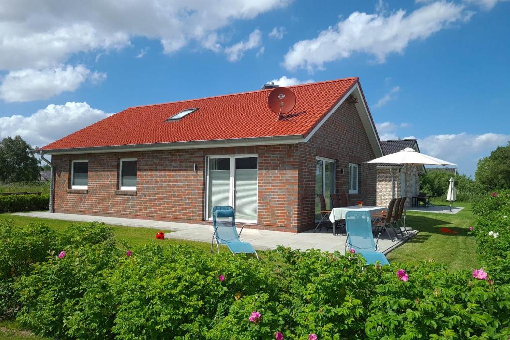 a small red brick house with a table and chairs at Haus JADEHUUS in Schweiburg