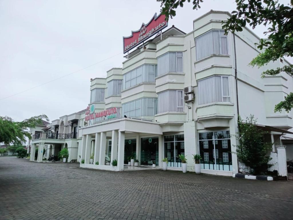 a large white building on a brick street at Hotel Mangkuto Syariah in Payakumbuh