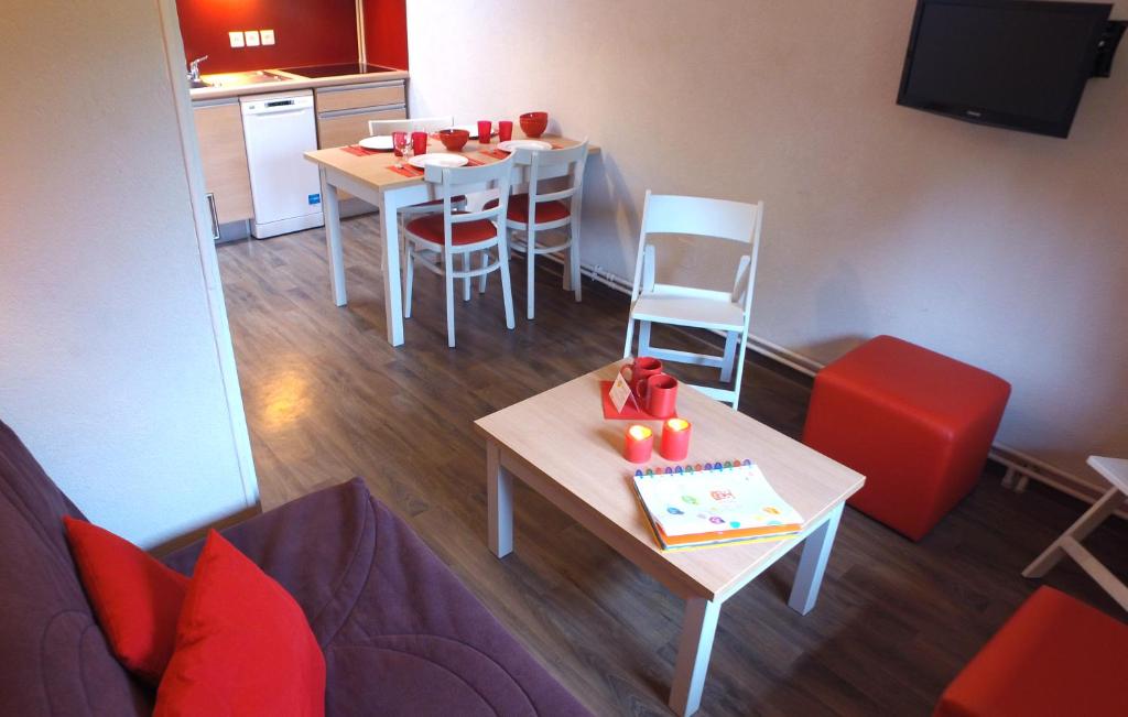 a living room with a table and chairs and a kitchen at VVF Saint-Lary-Soulan Hautes-Pyrénées in Saint-Lary-Soulan