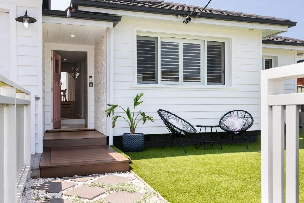 a white house with two chairs on the front lawn at Saltwater Cottage in Windang