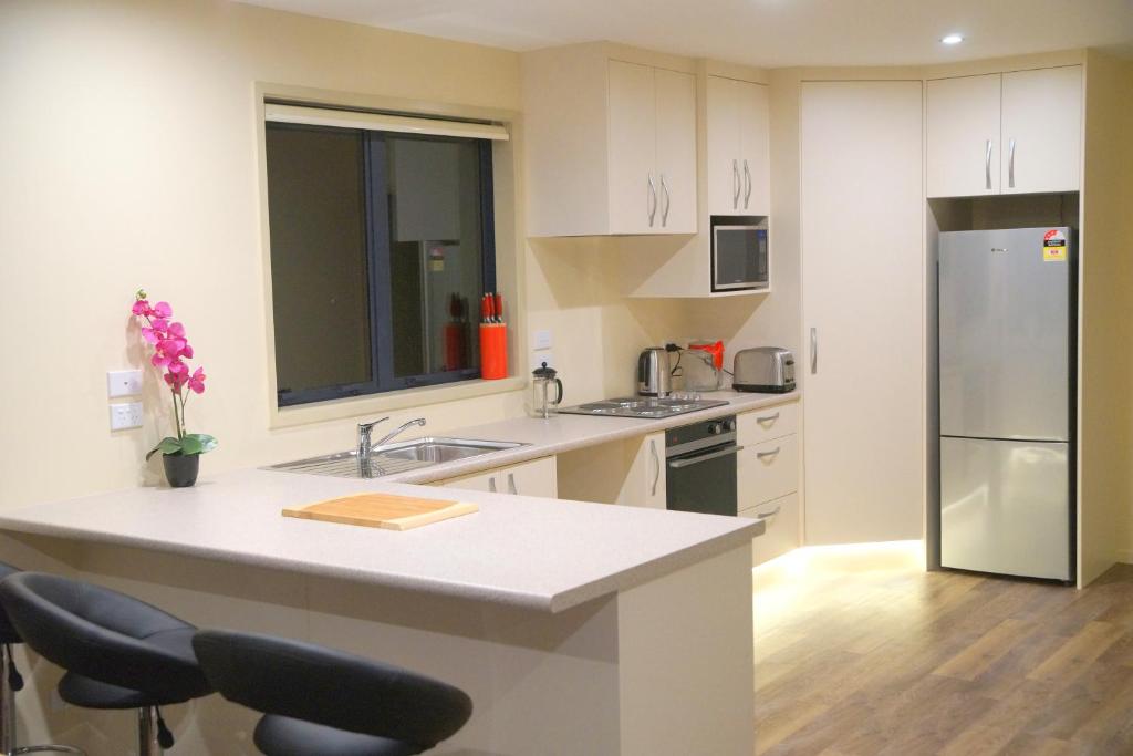 a kitchen with white cabinets and a kitchen island with chairs at A Touch of Class in Greymouth