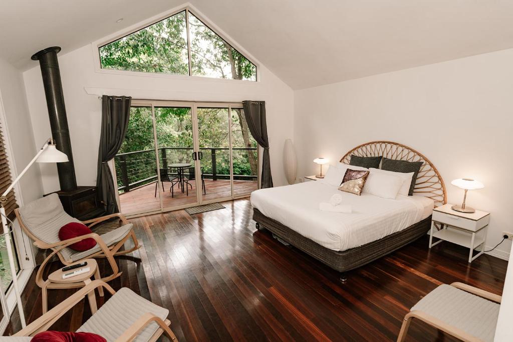 a bedroom with a bed and a large window at Shambala Estate Cottages in Mount Tamborine