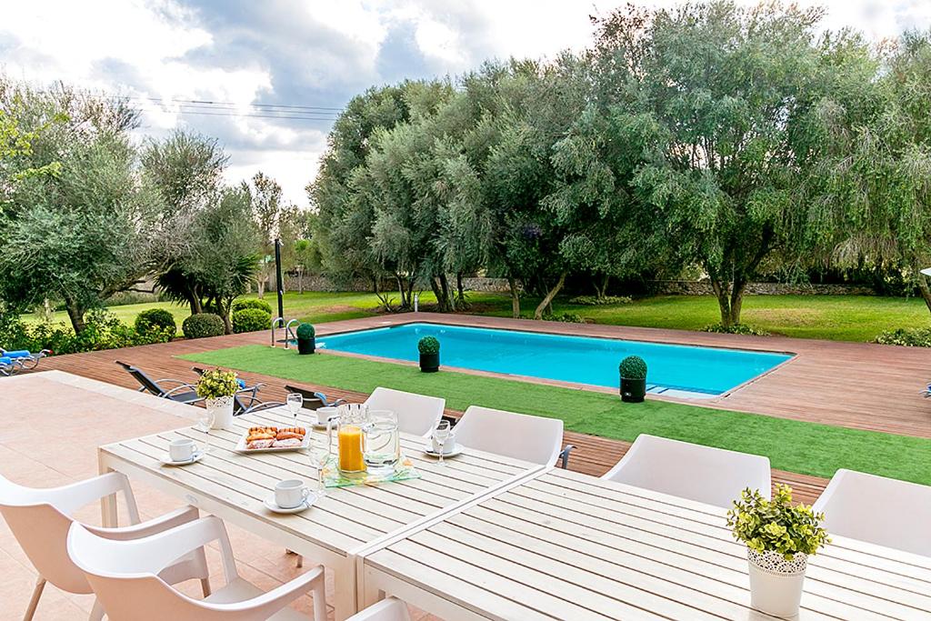 einen weißen Tisch und Stühle im Garten mit Pool in der Unterkunft Finca Santa Maria in Alcúdia