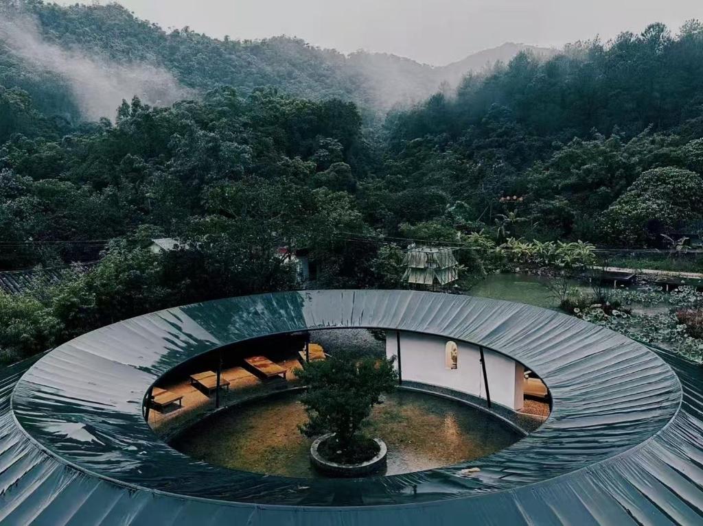 a circular building with a pond in front of a mountain at Limu Mountain Forest Park in Hainan