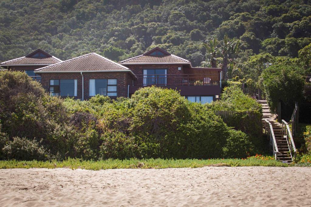 uma casa situada no topo de uma colina ao lado de uma praia em Archrock Resort em Plettenberg Bay