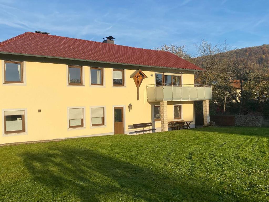 a large yellow house with a grass yard at Ferienwohnung am Breitenbach in Ebermannstadt