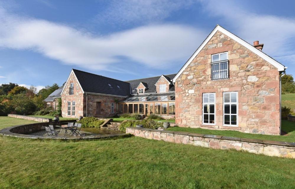 a large stone house with a pond in front of it at Quarryfield in Inverness