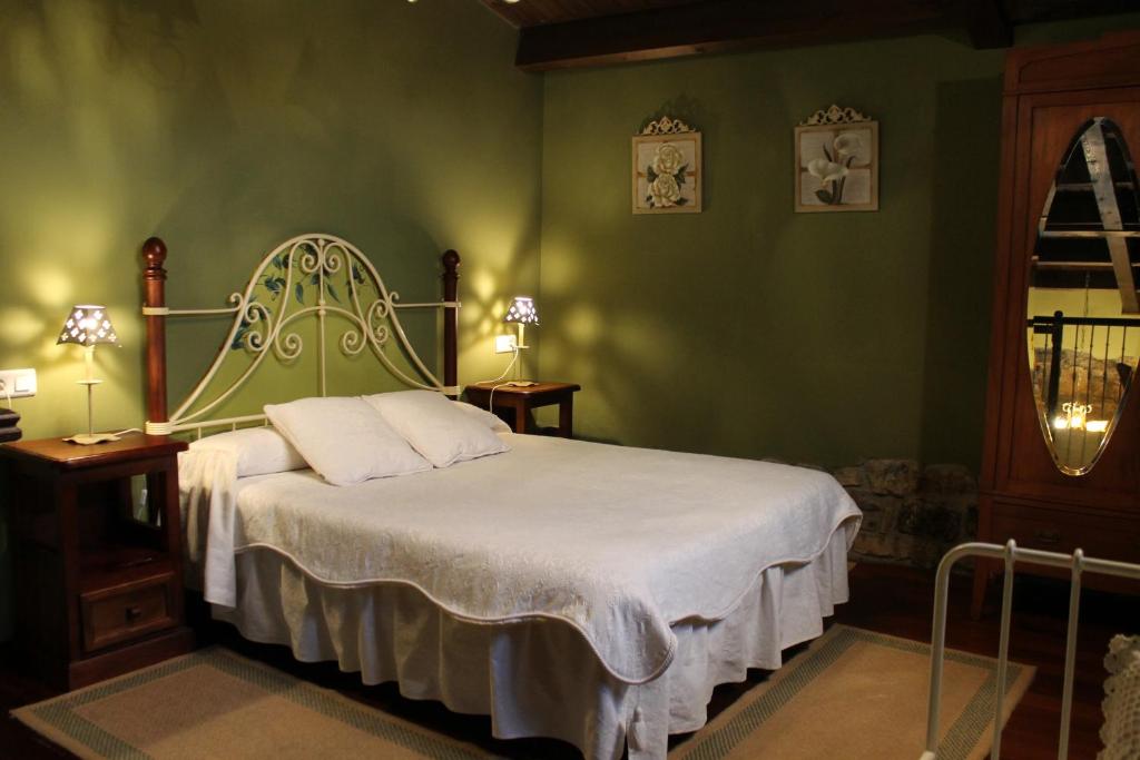 een slaapkamer met een bed met een groene muur bij Rodiles Rural Apartamentos in Selorio